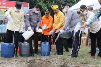 Kapolres bersama Forkopimda Parimo menunag miras ke dalam lubang pada pemusnaha miras hasil operasi pekat di parigi, Kamis (12/3/2026). (©Humas Polres Parimo)