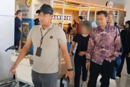 Petugas mengawal tersangka kasus dugaan tindak pidana perbankan. (©OJK)