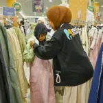 Relawan RUmah Dua Jari memakaikan baju baru kepad aseorang anak pada Belanja Bahagia Bersama Dhuafa di PGM Palu, Jumat (6/3/2026). (©bmzIMAGES/Basri Marzuki)