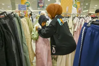 Relawan RUmah Dua Jari memakaikan baju baru kepad aseorang anak pada Belanja Bahagia Bersama Dhuafa di PGM Palu, Jumat (6/3/2026). (©bmzIMAGES/Basri Marzuki)