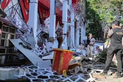 Warga berada di dekat reruntuhan gedung akibat gempa 7.6 M di Manado, Kamis (2/4/2026). (©AFP/Tonny Rarung/CNN)