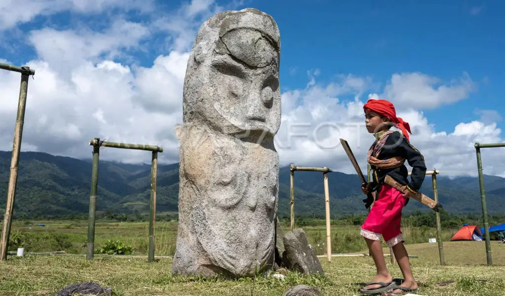 Seorang anak mengenakan pakaian adat melintas di depan patung Tadulako di situs Cagar Budaya Tadulako di Desa Bariri, Lore Tengah, Poso, Sulawesi Tengah, Jumat (16/6/2023). (©ANTARA FOTO/Basri Marzuki)