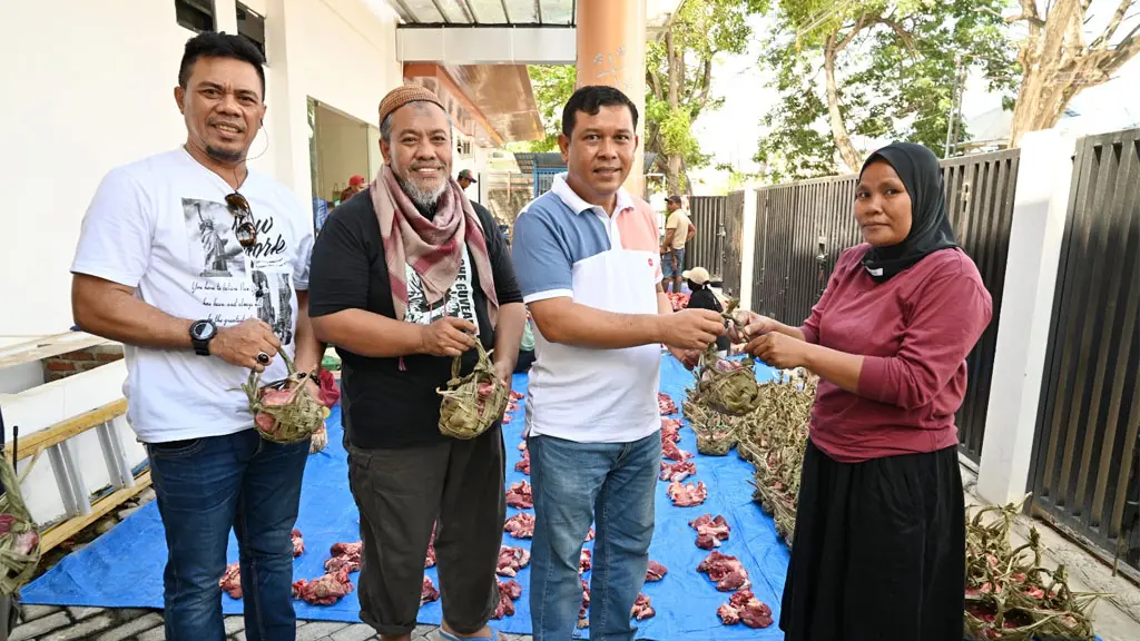 Kepala DLH Kota Palu Mohammad Arif Lamakarate (kedua kanan) bersama Sekretaris DLH Ibnu Mundzir (kedua kiri) dan Kabid Pengelolaan Sampah dan Limbah B3 DLH Hisyam Baba (kiri) menyerahkan daging kurban yang dikemas dengan Kamboti kepada warga di Kantor DLH Kota Palu, Kamis (28/5/2026). (©bmzIMAGES/Basri Marzuki)