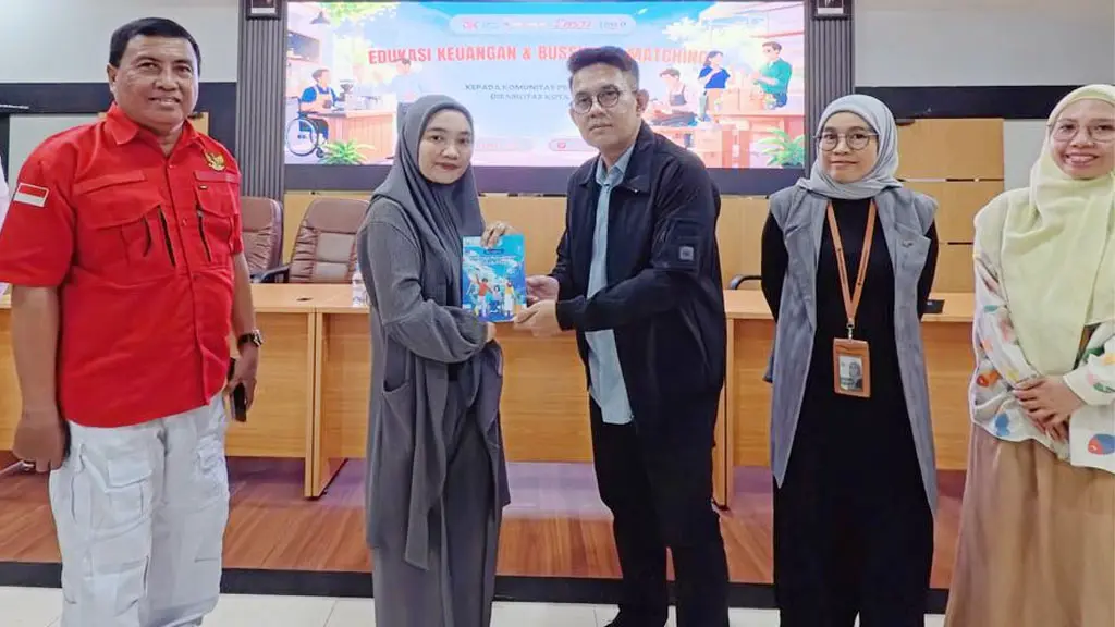 Kepala OJK Sulteng Bony Hardi Putra menyerahkan buku kepada peserta literasi keuangan di Palu. (©OJK Sulteng)